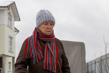 elderly woman in her yard outside the city in winter. An elderly woman in the fresh air.