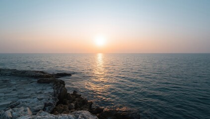 Fototapeta premium Dawn scene with peaceful water and rocky shoreline, emphasizing tranquil sea and sky for travel or nature layouts
