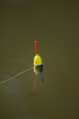 a fishing float, also known as a bobber, in the water. Fishing floats are used as visual indicators for anglers, showing when a fish is biting the ba