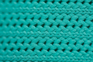 macro close-up of a textile, showing the texture of a wool fabric weave in a turquoise or teal color. 