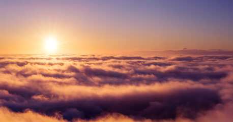 Golden sunrise above a sea of clouds, creating a calm and dreamy atmosphere. Warm morning light illuminates soft cloud layers, evoking freedom, serenity, and a sense of endless space.