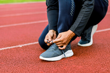 Runner tying shoelaces on athletic track preparing for race or workout