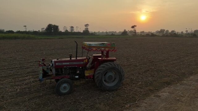 A tractor in Punjab Tractor in fields Punjab Tractor in a golden paddy field in a village of Okara, Punjab Pakistan Aerial Shot In sunset View 4K 
