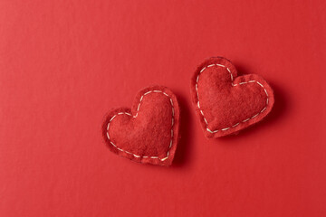 two stuffed red felt hearts on red background, monochromatic color fuzzy fabric texture with soft shadows, minimalist valentine's day romantic backgrounds or love with copy space