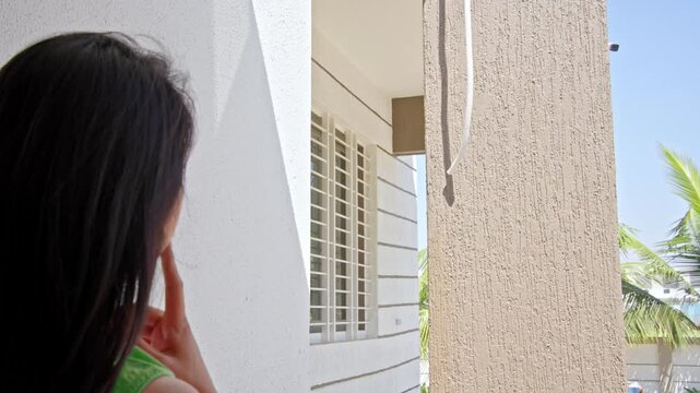 Indian Woman Worried About Water Dripping Leak Outside Home &ndash; AC Drain / Water Tank Leakage, Water Wastage, Maintenance Issue