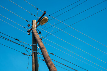 Weathered wooden electricity pole loaded with tangled power cables, ceramic insulators, and an old...