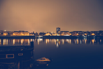 Night panorama of Novi Sad, Serbia, with illuminated city skyline beautifully reflected in the calm waters of Danube River for travel and urban nightlife