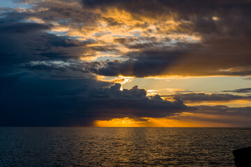 Golden rays break through dramatic storm clouds above the Adriatic Sea, illuminating the water with...