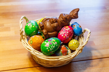 Basket with Easter eggs and Easter bunny on wooden table