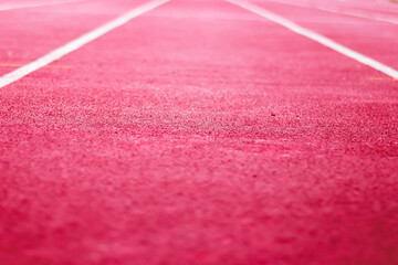Close-up of a vibrant pink running track with white lane lines receding into distance
