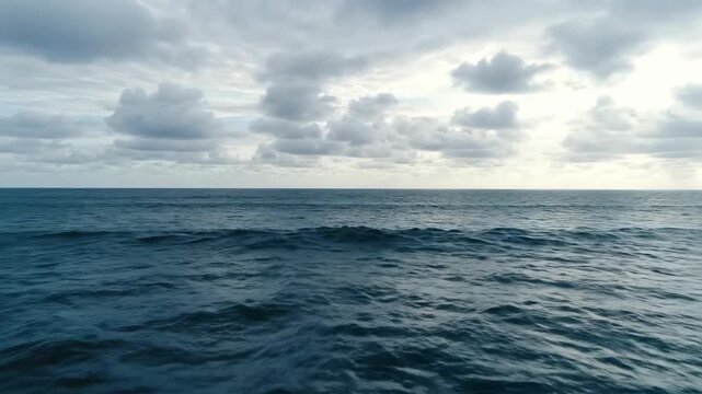 Wide aerial drone shot slowly gliding over deep textured ocean water meeting a perfectly flat cloudy sky horizon line cloudy sky horizon line, gliding, grey
