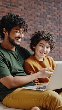 Father and son talk with friends on video call via laptop