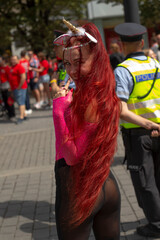 pensive performer posing with hand near face, playful smile and unicorn headband, pink mesh outfit, police