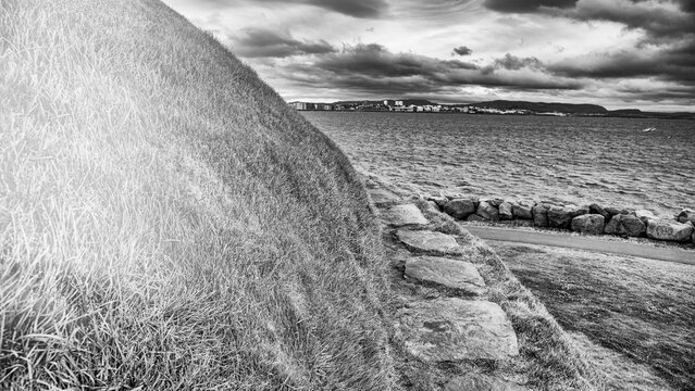 Scenic green hill near Reykjavik harbor Iceland with waterfront and city background - Powered by Adobe