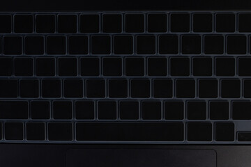Close-up of a modern laptop keyboard with backlit black keys, showcasing the illuminated white alphanumeric characters. Ideal for technology, computing, office, and digital themes.