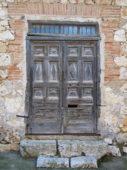 Old wooden door on rural stone facade