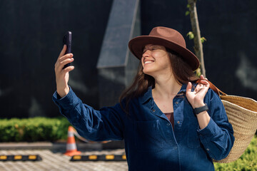 Woman smiles while taking selfie outside
