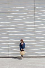 Woman standing alone by wavy wall in urban space