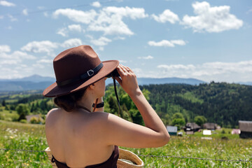 Woman uses binoculars to view landscape in summer