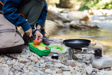 Camping by the river while cooking a simple meal