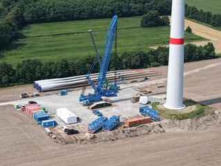 Assembly of a lattice boom crawler crane for the construction of a new wind turbine in the wind farm, aerial view, preparation, construction site, energy transition