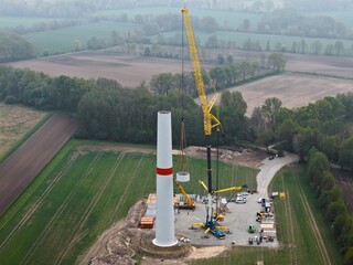 Heavy-duty crane lifts concrete part on the tower for a wind turbine, building construction, tower construction, wind energy, construction of a wind turbine, energy transition, aerial photo