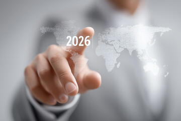 Businessman touches virtual world map highlighting 2026 as strategic global milestone.