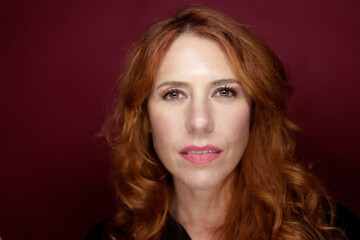 Fototapeta premium Woman with red hair posing on red background
