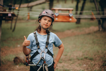 Confident Girl Giving OK Sign in Safety Harness at Adventure Park