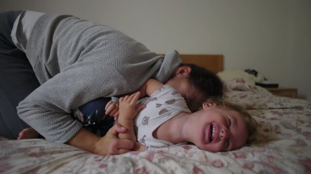 Woman playfully tickling toddler on bed during intimate family moment, joy, laughter, trust, affection, emotional bonding, everyday parenting connection inside home