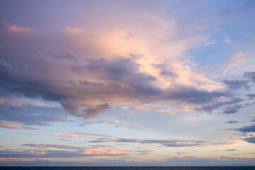 Delicate pink and lavender clouds drift across a serene evening sky above the calm Mediterranean...