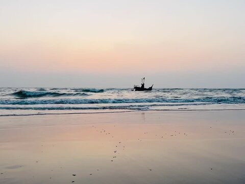 Peaceful Sunset Seascape With Gentle Ocean Waves and Traditional Fishing Boat