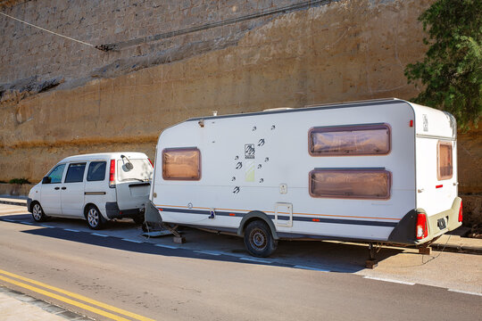 Valletta, Malta - November 29, 2025: A white car with a KNAUS Motorhome or Caravan parked by the road along a large stone wall