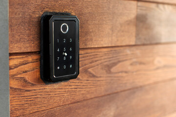 Keypad entry system installed on wooden wall, device allows users to enter code for access, closeup shot, free space