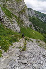 Fototapeta premium Hiker Walking Along Massive Rock Wall