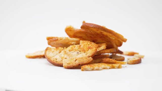 Curved baked bread slices rotate gently in a clean studio scene. The video emphasizes crisp edges, toasted surfaces, and light seasoning with a smooth rotation.