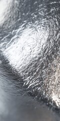 Abstract metallic texture with shimmering light and dark contrasts.