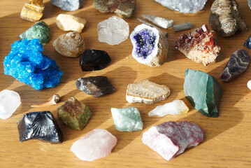Collection of diverse natural mineral specimens and crystals arranged on a wooden surface