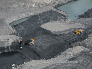 Aerial view of open pit coal mine with mining vehicles and water bodies