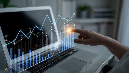Visual representation of data analytics where a hand interacts with dynamic graphs on a laptop screen, symbolizing business progress and technological integration in a modern workspace. Scalp