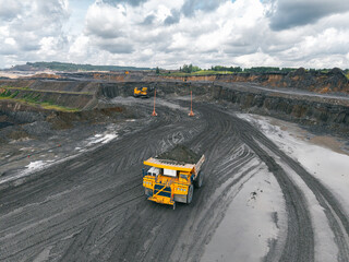 Industrial coal deposit development, machinery at open pit mine extracting resources. Aerial top view large quarry truck with overburden soil.