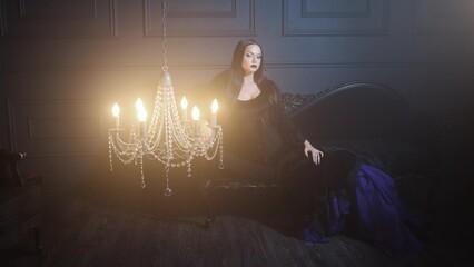 Gothic femme fatale in black godet dress and corset, dark elegant interior.