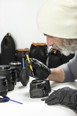 Technician repairing DSLR camera with precision tools, lenses and cleaning equipment. Concept of photography service, camera maintenance, repair workshop, technology care.