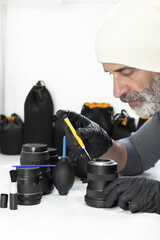 Technician repairing camera lens with precision tools in studio. Concept of photography service, lens maintenance, optical repair, professional equipment care.
