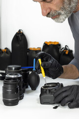 Technician repairing DSLR camera with precision tools, lenses and cleaning equipment. Concept of photography service, camera maintenance, repair workshop, technology care.