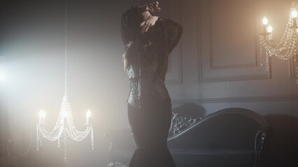 Gothic femme fatale in black godet dress and corset, dark elegant interior.