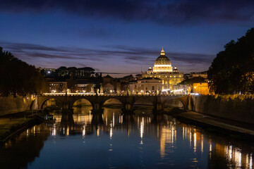 Obraz premium View of St. Peter's Basilica in Vatican City and the Sant'Angelo Bridge and the Tiber River, from the Umberto I Bridge, at dusk in Rome, Italy.