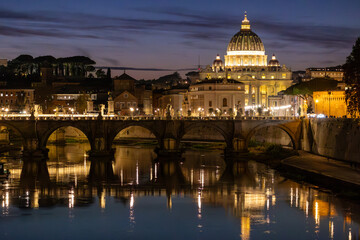 Fototapeta premium View of St. Peter's Basilica in Vatican City and the Sant'Angelo Bridge and the Tiber River, from the Umberto I Bridge, at dusk in Rome, Italy.