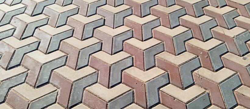 Top-down view of interlocking colored concrete pavement blocks arranged in a geometric zigzag pattern, ideal for architectural, outdoor flooring, and civil engineering visuals