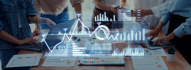 A diverse team collaborates on data analysis, utilizing laptops and tablets in a modern office. Graphs and charts display important metrics and insights for strategic planning. Scalp